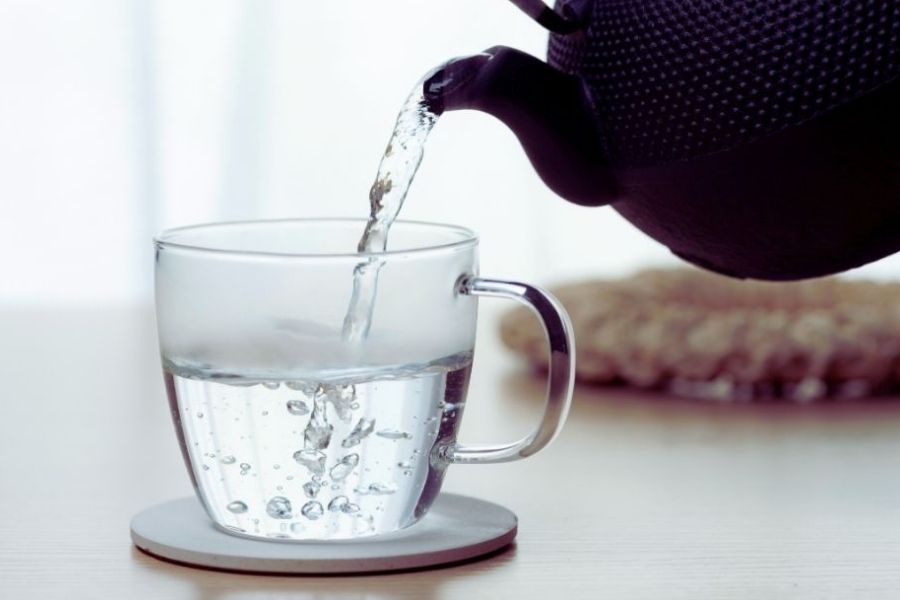 Nalévání horké vody z konvice do šálku.